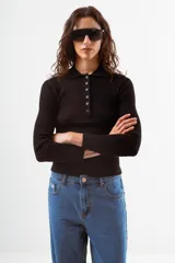 Top de tejido de punto acanalado color negro, de manga larga y cuello polo con botones frontales.