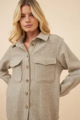 Camisa estilo leñador color beige con textura en espiga, de manga larga, con cuello clásico, cierre frontal con botones, dos bolsillos de parche con solapa abotonada en el pecho y puños abotonados. Confeccionada en lana fina sin teñir.