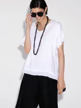 Blusa blanca de lino con cuello redondo y mangas cortas con terminación desflecada.