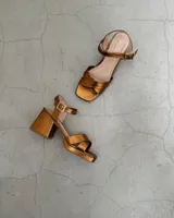 Sandalias de cuero color bronce, con taco cuadrado y tiras cruzadas en el empeine.