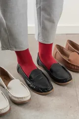 Mocasines de cuero color dorado con acabado texturizado, diseño clásico de punta redondeada y costuras visibles en el empeine. Cuentan con suela plana y flexible.