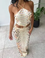 Vestido midi con estampado de piel de serpiente en tonos beige y marrón. Diseño con top halter y falda tubo con abertura lateral.
