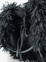 Cartera de diseño amplio y estructura flexible, confeccionada en textura de pelo sintético que aporta volumen. Cuenta con asas cortas integradas para llevar al hombro o en la mano.