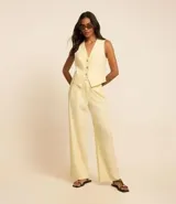 Pantalón wide leg color amarillo pálido confeccionado en viscolino, con tiro alto, trabilla con cinturón en metal, hebilla redonda y cierre por encaixe.