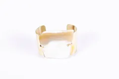 Brazalete rígido dorado con aplique central de guampa irregular color blanco y marrón claro.