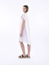 Vestido camisero de corte holgado y diseño asimétrico, con cuello clásico, cierre frontal de botones y mangas cortas.