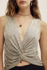Top metalizado de color dorado con escote en V pronunciado y detalle de nudo drapeado en la parte frontal. Sin mangas y de corte ajustado.