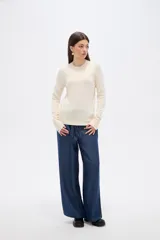 Sweater de lyocell al cuerpo, con cuello redondo a la base y mangas largas con detalle de botones en los puños.