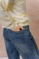 Jean wide leg de tiro medio-alto en denim azul medio con lavado desgastado. Presenta diseño de cinco bolsillos, cierre con botón y cremallera, y pierna amplia de caída recta.