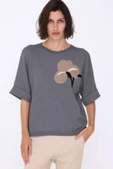Sweater gris de manga corta con bordado de flor en el frente.