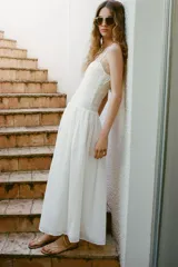 Vestido midi blanco de escote recto y tirantes finos ajustables. Presenta un torso elástico tipo nido de abeja con detalle de flores bordadas al tono en la parte superior y una falda de caída fluida con bolsillos laterales ocultos.