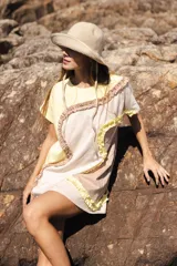 Vestido corto de algodón con diseño asimétrico de paneles en tonos amarillo, beige y arena, decorado con volados en las costuras curvas. Presenta cuello redondo, mangas cortas y un corte relajado.