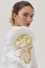 Camisa blanca de mezcla lino-algodón, con corte recto y mangas clásicas. Presenta un bordado floral en el hombro con distintas técnicas y canutillos.