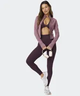 Campera Fabletics modelo Perfect Storm Cropped, de color rosado con cierre frontal completo, cuello alto, mangas largas con aberturas para pulgares y bolsillos laterales.