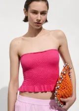 Top strapless de punto fruncido en color fucsia, con diseño crop y detalle de volante en el ruedo.