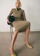 Vestido midi de punto canalé con cuello perkins y cierre frontal de cremallera. Presenta un diseño entallado de manga larga.