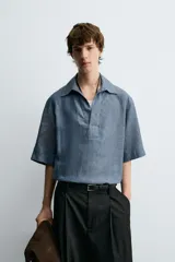 Camisa polo de calce relajado confeccionada en tejido de lino color azul. Presenta cuello solapa con abertura frontal en V y manga corta.