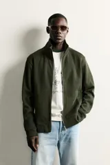 Chaqueta regular fit de cuello subido, confeccionada en tejido técnico interlock de algodón con elasticidad. Presenta cierre frontal con cremallera, manga larga con puños en rib y bolsillos de vivo en la cadera.