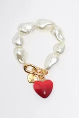 Pulsera elástica compuesta por perlas barrocas de gran tamaño y dijes colgantes: un corazón metálico dorado con logo grabado y un corazón grande de color rojo.