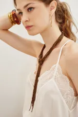 Collar largo compuesto por múltiples hilos de mostacillas de vidrio en tono bronce, diseñado para llevarse con un nudo decorativo en el frente.