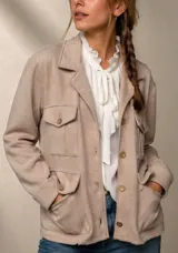 Chaqueta de tejido de punto en color beige, con diseño tipo safari, cuello solapa, cierre frontal con botones y cuatro bolsillos delanteros con solapa.