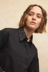 Camisa blanca de algodón con cuello clásico y mangas largas. Detalle de tachas plateadas en el cuello.