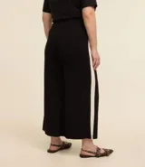 Pantalón pantacourt negro con raya lateral blanca, confeccionado en viscosa y elastano.