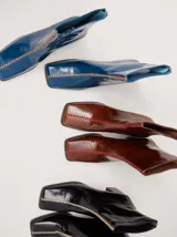 Botas de caña media color marrón, confeccionadas en cuero con acabado brillante. Presentan punta cuadrada, taco de madera y un distintivo bordado decorativo en color rojo que recorre el empeine hasta la punta.