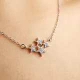 Collar dorado con cadena fina y dije de tres estrellas con incrustaciones de strass.