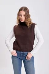 Chaleco de punto en color marrón, con cuello alto y diseño sin mangas. Presenta un tejido de punto liso y corte holgado.