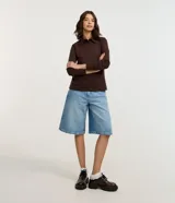 Blusa tipo polo de manga larga, confeccionada en tejido interlock de algodón y poliéster. Presenta cuello clásico con cierre frontal de botones y diseño básico liso.