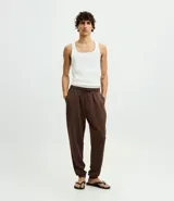 Pantalón de pijama tipo jogger color marrón, con cintura elástica ajustable mediante cordón, bolsillos laterales y puños en los tobillos.