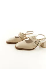 Zapatos tipo Mary Jane de charol color negro, con taco bloque, talón descubierto y doble tira frontal con hebillas metálicas.