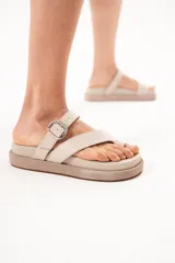 Sandalias de cuero color arena, con diseño de tiras cruzadas, sujetador para el dedo y hebilla metálica lateral. Cuenta con suela acolchada y plataforma plana forrada.