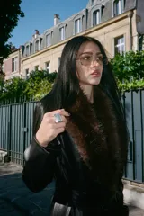 Abrigo largo negro de efecto piel con cuello de pelo sintético desmontable, solapas con muescas, manga larga, bolsillos laterales, forro interior a tono y cierre frontal con botones. Incluye cinturón del mismo material para ajustar a la cintura.