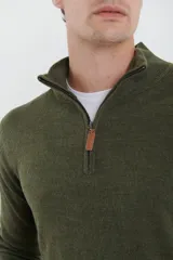 Sweater verde oliva de tejido acrílico con textura similar al cashmere, corte clásico, cuello alto con cierre metálico y tirador de cuerina ecológica.