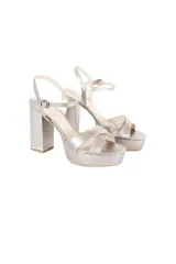 Sandalia de fiesta con plataforma y taco cuadrado alto, confeccionada en cuero con acabado metalizado color peltre. Presenta tiras cruzadas en el empeine y cierre con pulsera ajustable al tobillo.