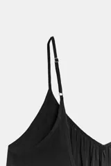 Vestido midi de color negro, confeccionado en tejido fluido, con escote en V y tirantes finos ajustables. Presenta frunces en el pecho y un volante en el bajo.