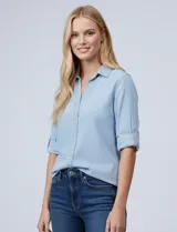 Camisa de tencel color celeste claro, con cuello con solapa, escote en V y abertura central con botones. Manga larga con presilla para ajustar el largo. El largo de espalda es mayor al delantero y tiene un tajo central.