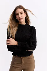 Blusa negra de algodón con textura fruncida en todo el cuerpo, cuello alto y puños con volados.