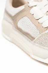 Championes de cuero legítimo en tonos arena y nude, decorados con microcristales en la capellada y laterales, con suela robusta y cordones anchos al tono.