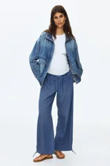 Pantalón de denim suave color azul, de corte holgado estilo globo con piernas abombadas, cintura elastizada con cordón ajustable y bajos con elástico y cintas para ajustar.