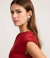 Top ajustado color rojo, con cuello redondo y mangas cortas tipo hombreras o almohadillas. El tejido parece ser de punto o viscosa con buena caída y presenta un fruncido horizontal a la altura de la cintura.