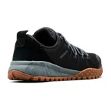 Championes Columbia modelo Fairbanks Low, color negro con suela de caucho color caramelo y mediasuela gris. Presentan un diseño técnico con empeine de malla transpirable, sistema de cordones reforzados y puntera protegida.