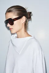 Camiseta blanca de manga larga con cuello redondo y superposición de tela tipo pañuelo.