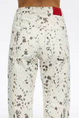 Pantalón de denim de corte recto y tiro alto, con diseño de cinco bolsillos y cierre frontal con botón y cremallera. Presenta un estampado de manchas oscuras sobre base de color terracota.