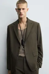 Blazer de corte slim fit en color verde oscuro, con cuello de solapas de muesca, cierre frontal de un botón, bolsillos laterales con solapa y bolsillo de vivo en el pecho.