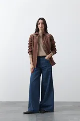 Sobrecamisa de gamuza color marrón con bordados decorativos estilo western en la zona de los hombros y cierre frontal con botones metálicos.