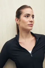 Campera deportiva de textura acanalada, color negro, con cierre frontal, cuello alto y mangas largas con orificio para el pulgar.