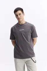 Remera de manga corta color gris oscuro, con escote redondo, ajuste regular y estampado frontal con la palabra "POSITIVE" en estilo graffiti.